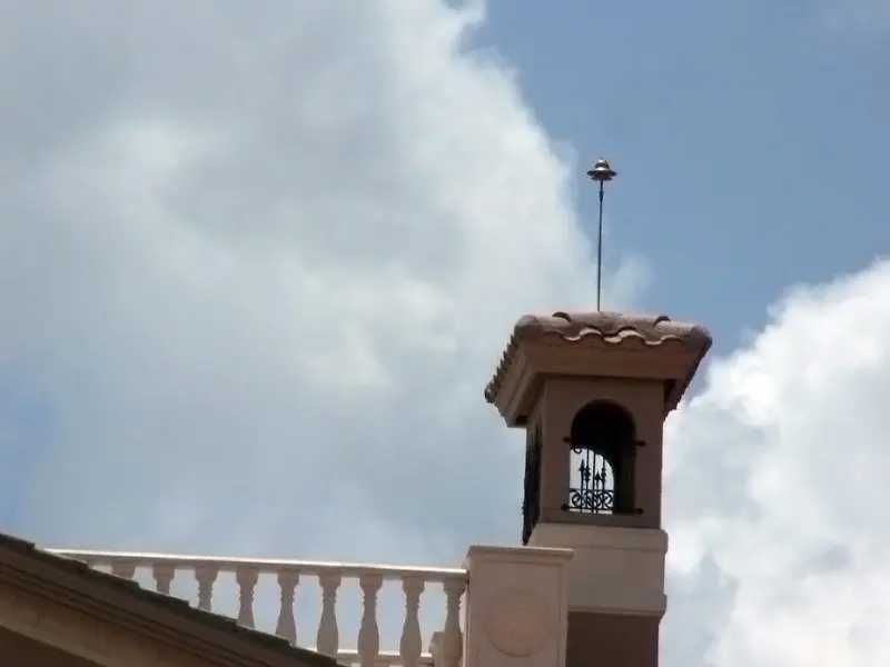 Close-up of a slim Preventor air terminal mounted on a tile roof ridge against a clear sky