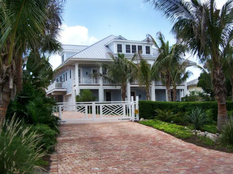 Florida home with palms and a darkening storm sky building behind the roofline